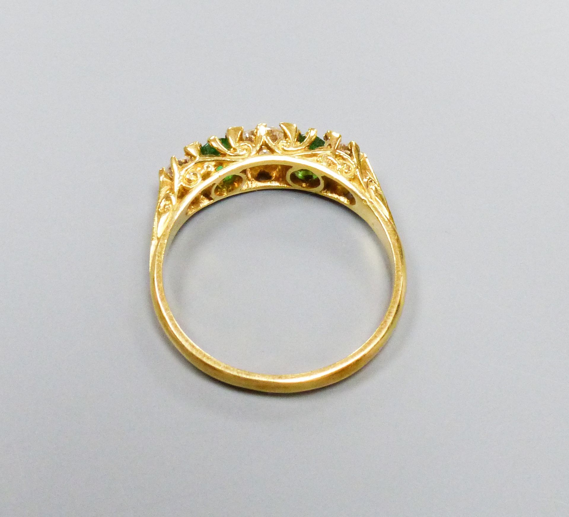 A modern Victorian style 18ct gold, three stone diamond and two stone emerald set half hoop ring, size P, gross weight 3.4 grams.